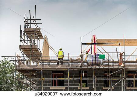 Stock Photo - Worker working on roof of building. Fotosearch