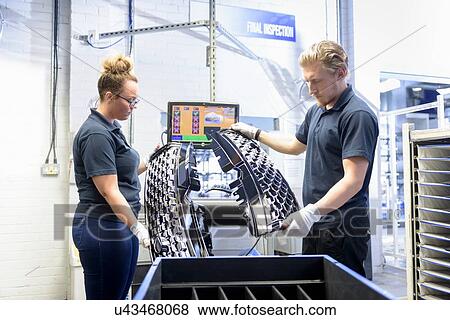 Stock Photo - Workers checking paint finish on automotive parts in spray paint factory. Fotosearch