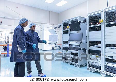 Stock Image - Workers in clean room in electronics factory. Fotosearch