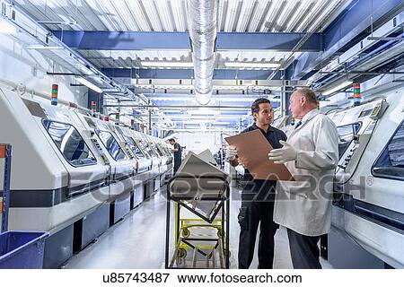 Stock Photo - Workers in discussion in circuit board manufacturing factory. Fotosearch