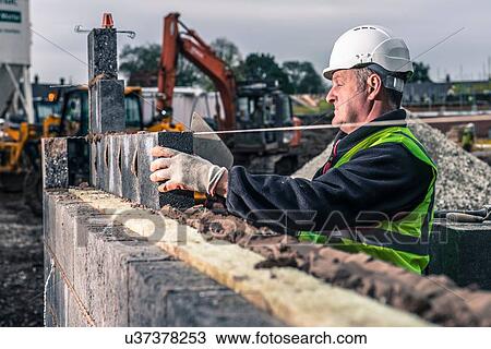 Workers laying bricks on construction site View Large Photo Image Stock Image - Workers laying bricks on construction site. Fotosearch
