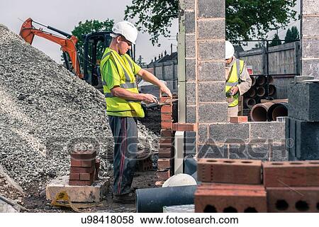 Workers laying bricks on construction site View Large Photo Image Stock Photo - Workers laying bricks on construction site. Fotosearch