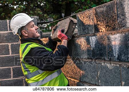 Stock Photograph - Workers laying bricks on construction site. Fotosearch