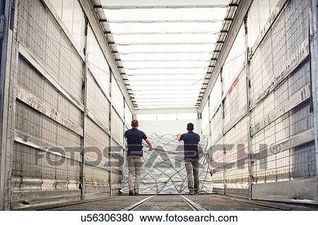 Stock Image - Workers pushing freight in air freight container. Fotosearch