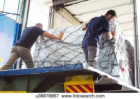 Stock Photo - Workers pushing freight into air freight container. Fotosearch