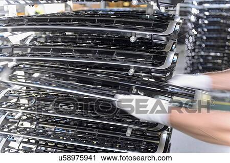 Stock Image - Workers with automotive parts in spray paint factory, close up. Fotosearch