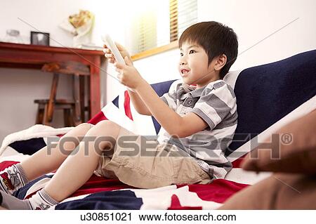 Young boy sitting on sofa watching the television at home View Large Photo Image Stock Image - Young boy sitting on sofa watching the television at home. Fotosearch