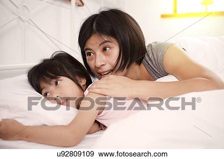 Young Chinese mother and daughter laying in bed together at home View Large Photo Image Stock Photo - Young Chinese mother and daughter laying in bed together at home. Fotosearch