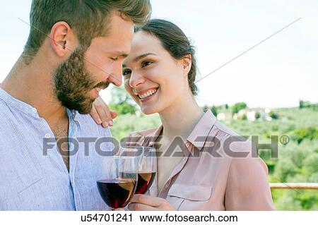 Young couple holding wine glasses face to face smiling View Large Photo Image Stock Image - Young couple holding wine glasses face to face smiling. Fotosearch