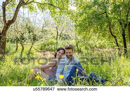 Young couple sitting back to back on grass looking down smiling View Large Photo Image Stock Photo - Young couple sitting back to back on grass looking down smiling. Fotosearch