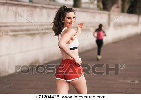 Young female runner looking over her shoulder whilst running View Large Photo Image Stock Photo - Young female runner looking over her shoulder whilst running. Fotosearch