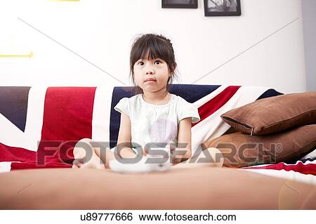 Young girl sitting on sofa watching the television at home View Large Photo Image Stock Photograph - Young girl sitting on sofa watching the television at home. Fotosearch