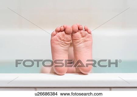 Picture - Young girl with feet on edge of bathtub. Fotosearch