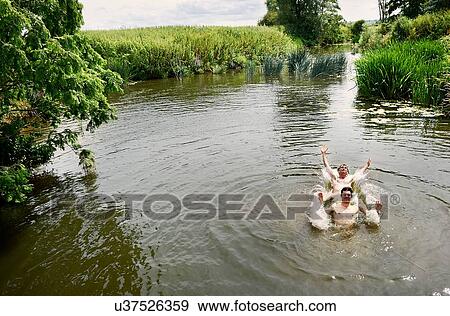 Stock Photo - Young man and teenage boy splashing in rural lake. Fotosearch