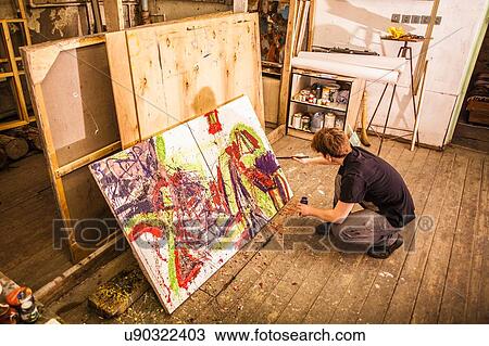 Young man painting on canvas in studio View Large Photo Image Stock Image - Young man painting on canvas in studio. Fotosearch