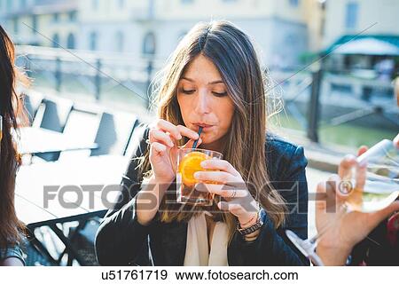 Young woman and friends drinking cocktails at waterfront cafe View Large Photo Image Stock Photo - Young woman and friends drinking cocktails at waterfront cafe. Fotosearch