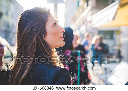 Young woman looking up from city street View Large Photo Image Stock Photograph - Young woman looking up from city street. Fotosearch