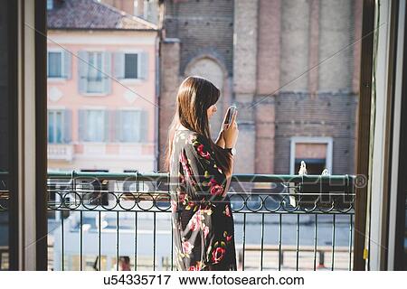 Young woman reading smartphone texts on city balcony View Large Photo Image Stock Photo - Young woman reading smartphone texts on city balcony. Fotosearch