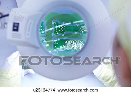Picture - Young woman using magnifier at quality check station at factory producing flexible electronic circuit boards. Plant is located in the south of China, in Zhuhai, Guangdong province. Fotosearch