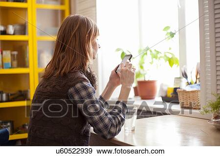Young woman using smartphone at table View Large Photo Image Stock Photo - Young woman using smartphone at table. Fotosearch