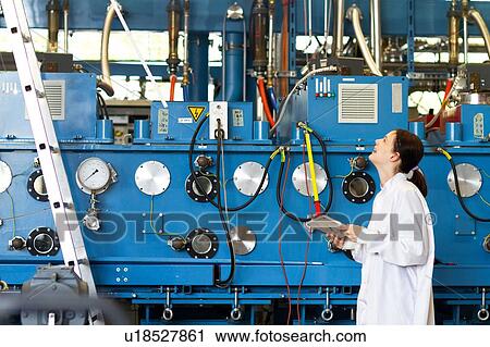 Young woman wearing lab coat holding digital tablet, looking up at scientific equipment smiling View Large Photo Image Stock Image - Young woman wearing lab coat holding digital tablet, looking up at scientific equipment smiling. Fotosearch