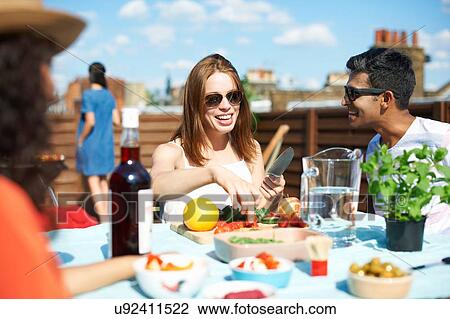 Stock Image - Adult friends preparing fresh finger food at rooftop party. Fotosearch
