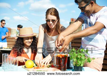 Adult friends preparing fruit for punch cocktail at rooftop party View Large Photo Image Stock Image - Adult friends preparing fruit for punch cocktail at rooftop party. Fotosearch