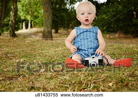 Baby girl sitting on grass with film camera looking at camera mouth open View Large Photo Image Stock Photography - Baby girl sitting on grass with film camera looking at camera mouth open. Fotosearch