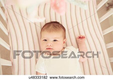 Stock Image - Baby lying in crib. Fotosearch