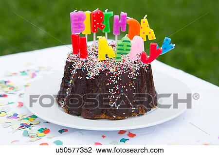 Stock Image - Birthday cake with candles on garden table. Fotosearch
