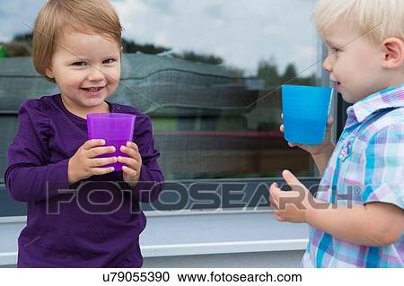 Boy and female toddler drinking from plastic cups on patio View Large Photo Image Stock Image - Boy and female toddler drinking from plastic cups on patio. Fotosearch