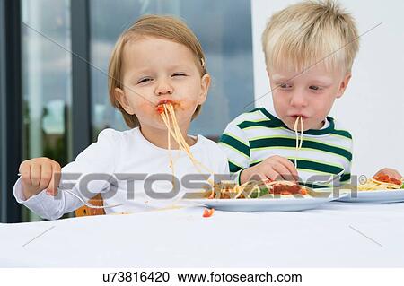 Boy and female toddler eating spaghetti on patio View Large Photo Image Stock Image - Boy and female toddler eating spaghetti on patio. Fotosearch