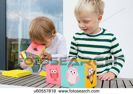 Stock Photo - Boy and female toddler playing with owl building blocks on patio. Fotosearch