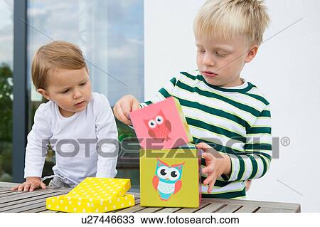 Boy and female toddler playing with building blocks on patio View Large Photo Image Stock Image - Boy and female toddler playing with building blocks on patio. Fotosearch