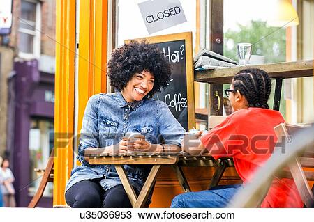 Stock Image - Boy and mother chatting at sidewalk cafe. Fotosearch