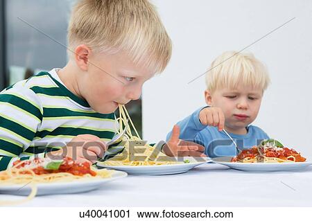 Boy and toddler brother eating spaghetti on patio View Large Photo Image Stock Image - Boy and toddler brother eating spaghetti on patio. Fotosearch