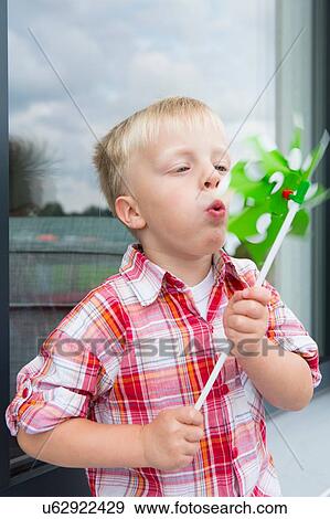 Boy blowing pinwheel on patio View Large Photo Image Stock Photo - Boy blowing pinwheel on patio. Fotosearch