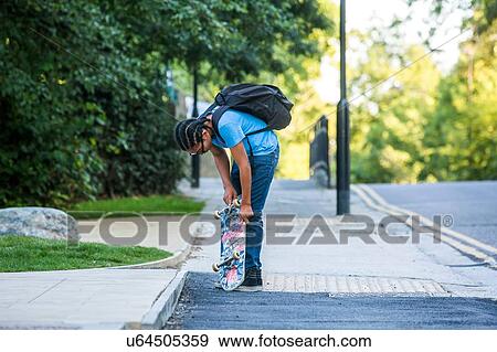 Boy checking his skateboard on sidewalk View Large Photo Image Stock Photo - Boy checking his skateboard on sidewalk. Fotosearch