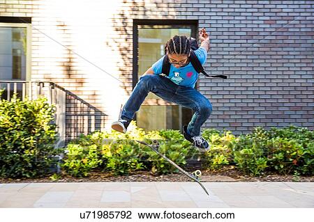 Boy doing skateboarding trick jump on urban sidewalk View Large Photo Image Stock Image - Boy doing skateboarding trick jump on urban sidewalk. Fotosearch