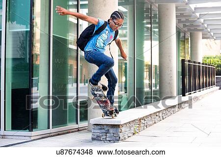 Boy doing skateboarding trick jump on urban wall View Large Photo Image Stock Photo - Boy doing skateboarding trick jump on urban wall. Fotosearch