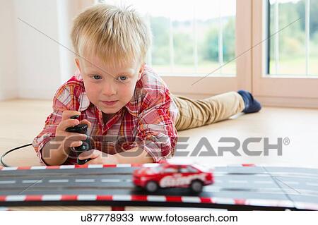Boy playing with toy racing car on living room floor View Large Photo Image Stock Image - Boy playing with toy racing car on living room floor. Fotosearch