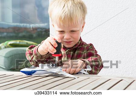 Picture - Boy preparing toy airplane on patio table. Fotosearch