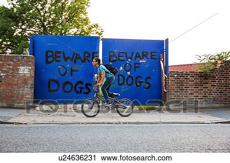 Stock Image - Boy riding BMX bicycle along urban sidewalk. Fotosearch