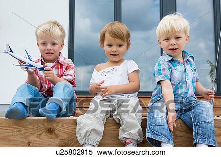 Stock Photography - Boy with toy airplane and two toddlers sitting on patio. Fotosearch