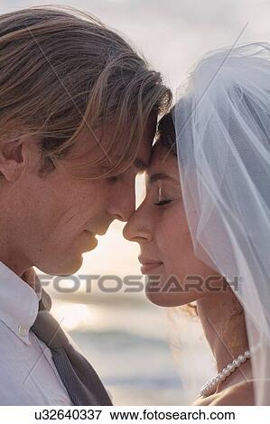 Stock Photo - Bride and groom, face to face, outdoors, sunsuet. Fotosearch