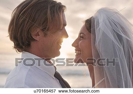 Stock Photo - Bride and groom, face to face, outdoors, sunset. Fotosearch