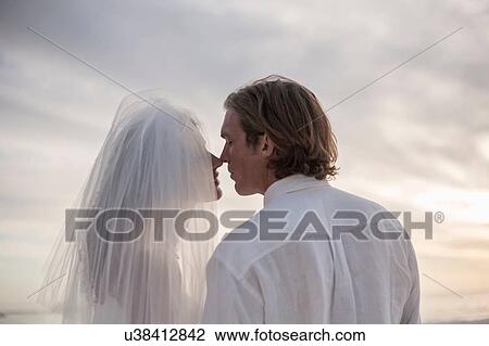 Bride and groom on beach, face to face, outdoors, rear view View Large Photo Image Stock Image - Bride and groom on beach, face to face, outdoors, rear view. Fotosearch