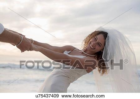 Bride and groom on beach, holding hands, fooling around, laughing View Large Photo Image Stock Photo - Bride and groom on beach, holding hands, fooling around, laughing. Fotosearch