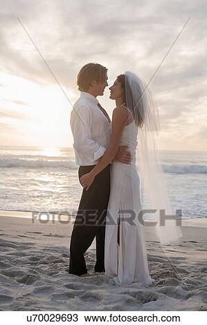 Bride and groom on beach, standing face to face View Large Photo Image Stock Image - Bride and groom on beach, standing face to face. Fotosearch