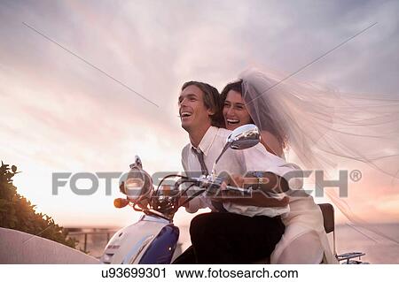 Bride and groom riding motorcycle on beach against sunset View Large Photo Image Stock Image - Bride and groom riding motorcycle on beach against sunset. Fotosearch